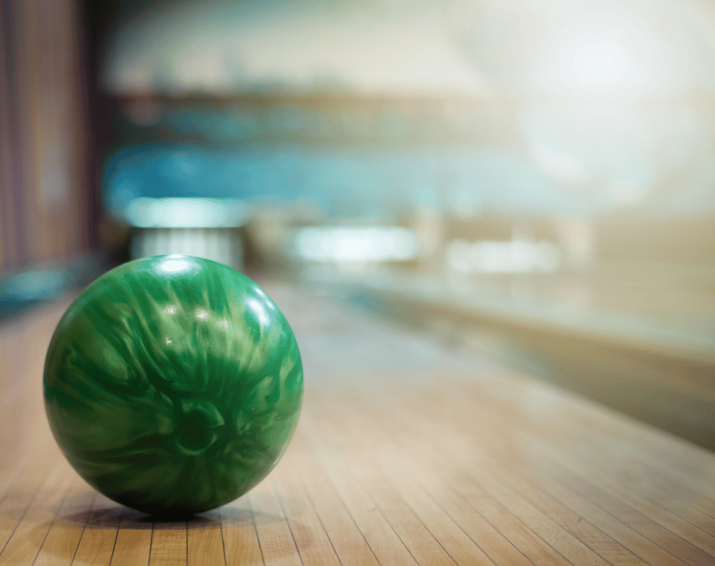 Image of a green bowling ball going towards the pins.