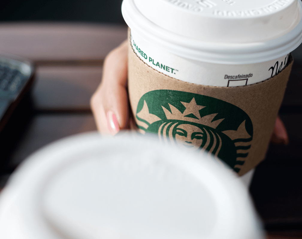 photo of a hand holding a starbucks coffee cup resting on a table