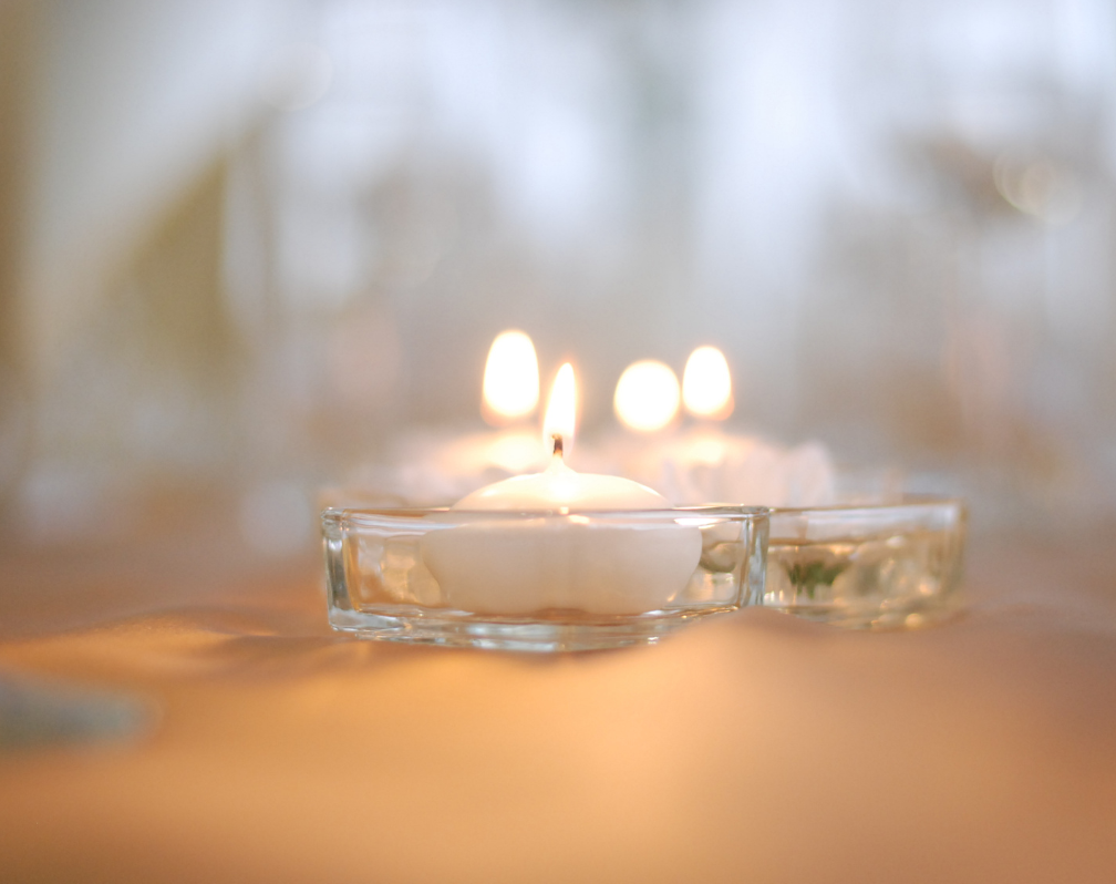image of a group of white candles lit with a flame against a white background
